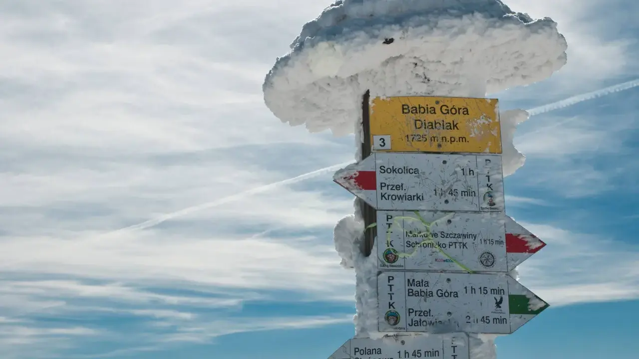 Znak szlaku na Babiej Górze, Diablak 1725 m n.p.m. w zimowej scenerii. Wskazuje kierunki do Sokolicy, Krowiarek i schroniska PTTK.