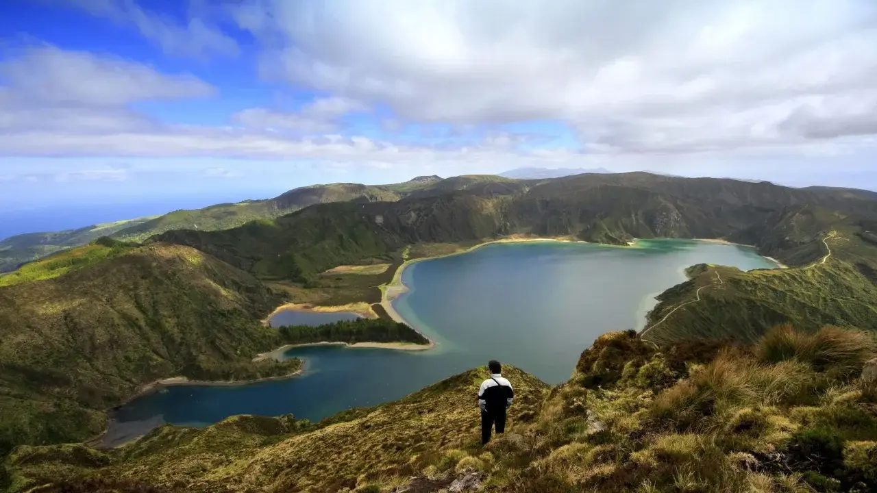 Ein Mann blickt auf eine atemberaubende Kraterlandschaft mit mehreren Seen. Die Frage, ob Madeira zu den Azoren gehört, wird hier durch die Schönheit der Natur beantwortet.