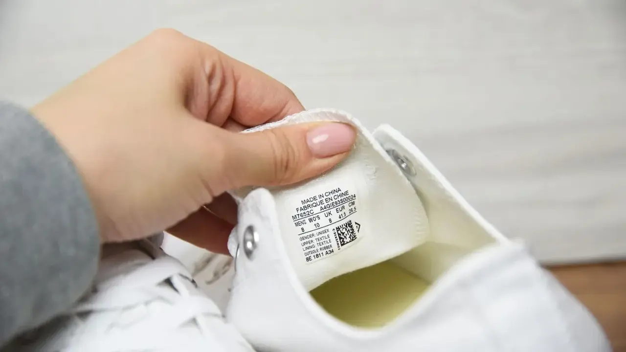 Dłoń pokazuje metkę z rozmiarem na białych butach Converse. Sprawdzamy, czy to oryginalne Converse, a nie podróbki.