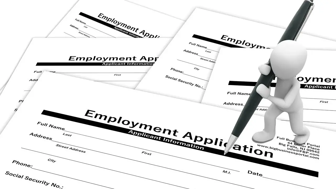 Biała figurka z długopisem wypełnia formularz "Employment Application" (ogłoszenie o pracę po ang.).