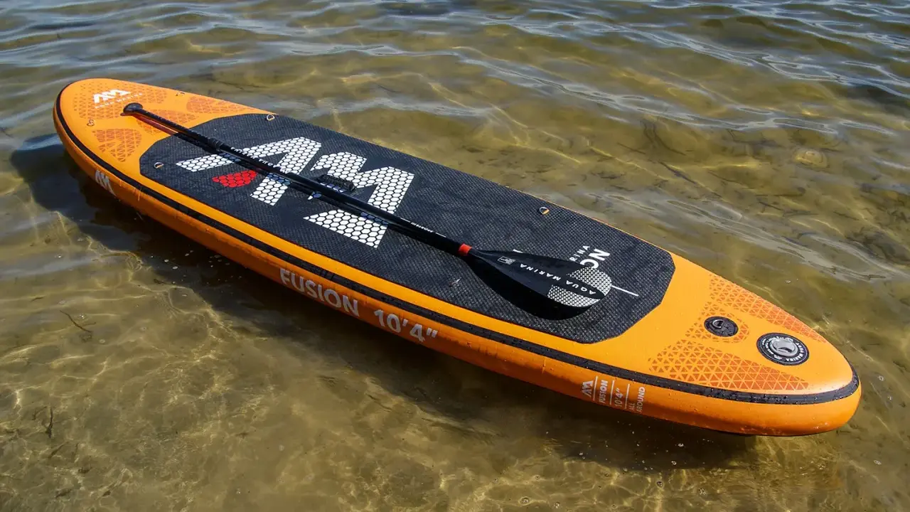 Pomarańczowy aquamarina sup z wiosłem leży na płytkiej, przejrzystej wodzie.