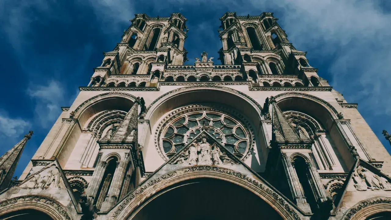 La **cathédrale de Laon**, majestueuse et imposante, se dresse sous un ciel bleu profond. Ses tours jumelles et sa rosace ornée captivent le regard.