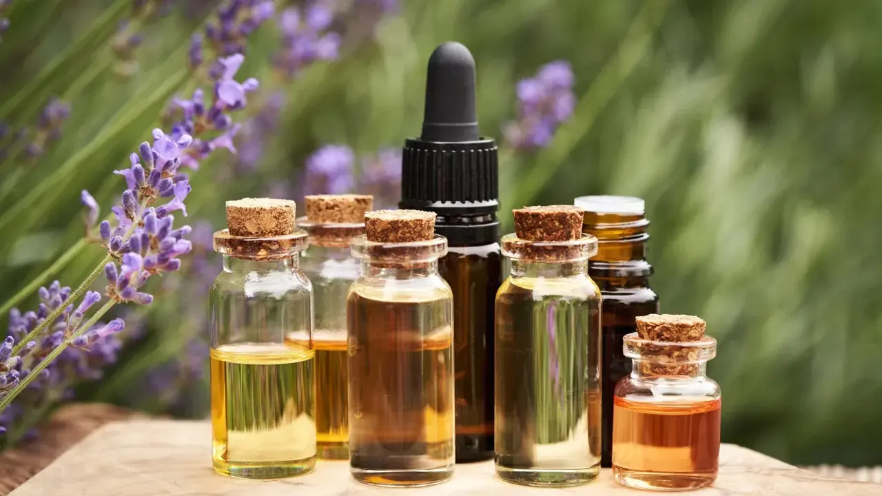 Bottigliette di oli essenziali, con lavanda sullo sfondo, che evocano le loro proprietà benefiche e naturali.