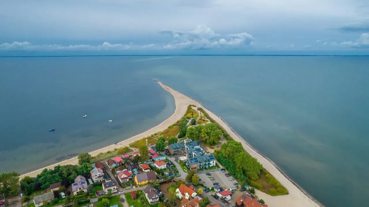Malownicza miejscowość nad morzem z domkami i plażą, otoczona wodą.