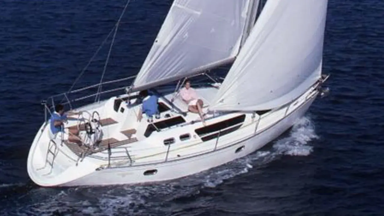Trois personnes profitent d'une belle journée en mer à bord de voiliers occasion 9 10 mètres. Le bateau blanc navigue sur des eaux bleues.