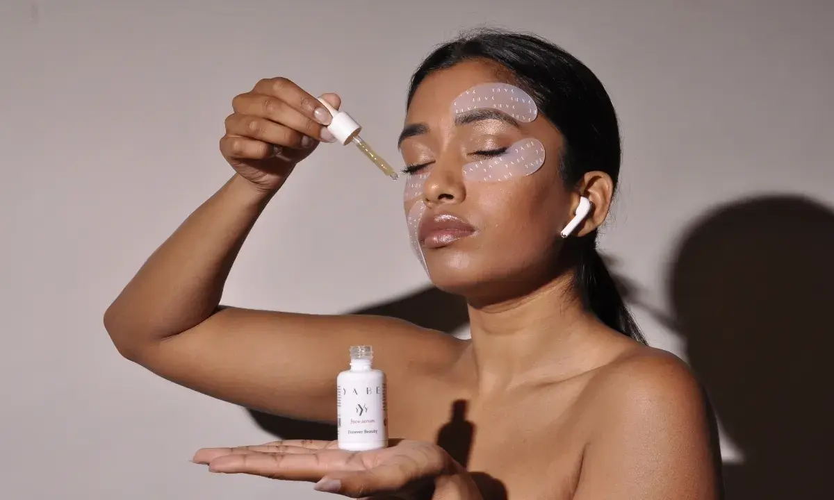 Donna applica siero con contagocce, ha maschera occhi e auricolari. Chissà ogni quanto maschera occhi per un viso radioso.