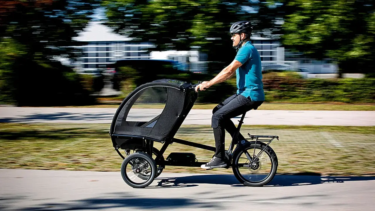 Mann fährt ein Lastenrad mit Kabine, ideal für lastenrad erwachsene transportieren.
