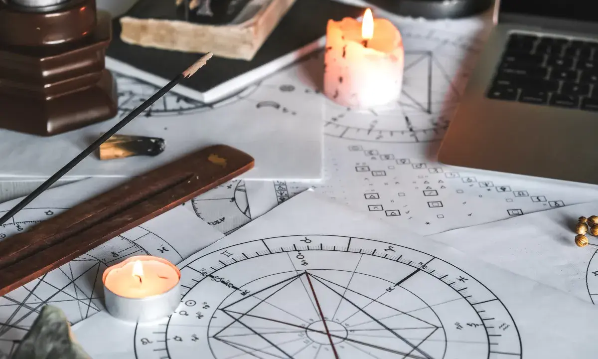 Świece i kadzidełka tworzą mistyczną atmosferę wokół kart astrologicznych. 11 dom astrologia w centrum uwagi.
