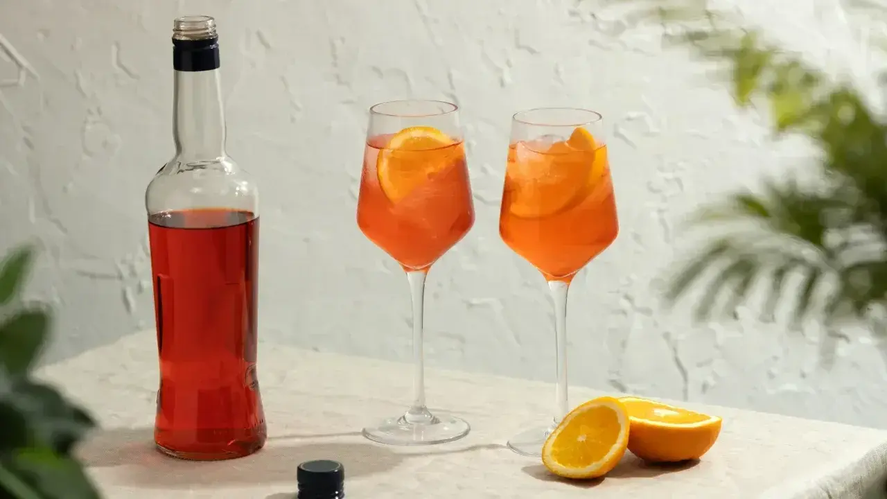 Butelka Aperolu i dwa drinki z pomarańczą, idealne proporcje na letnie popołudnie.