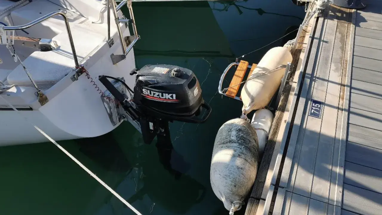 Un voilier "love love" amarré au ponton, avec un moteur Suzuki prêt à l'action. Des pare-battages protègent la coque.
