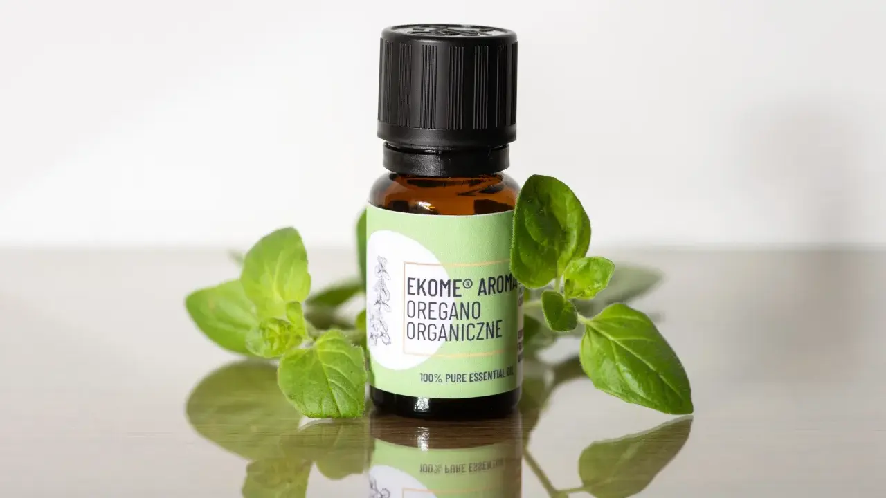 Szukasz, gdzie kupić olejek z oregano? Na zdjęciu buteleczka z organicznym olejkiem z oregano, otoczona świeżymi gałązkami.