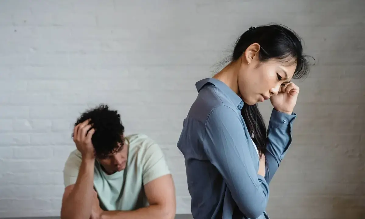Pareja en silencio, ella con la mano en la frente, él con la cabeza entre las manos. Un ambiente de tensión pasivo agresivo.