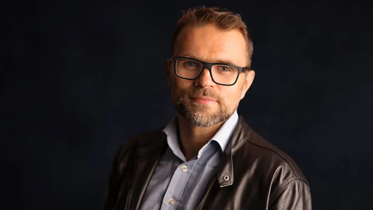 Jacek Bartosiak, autor książek, w okularach i skórzanej kurtce, patrzy w obiektyw.