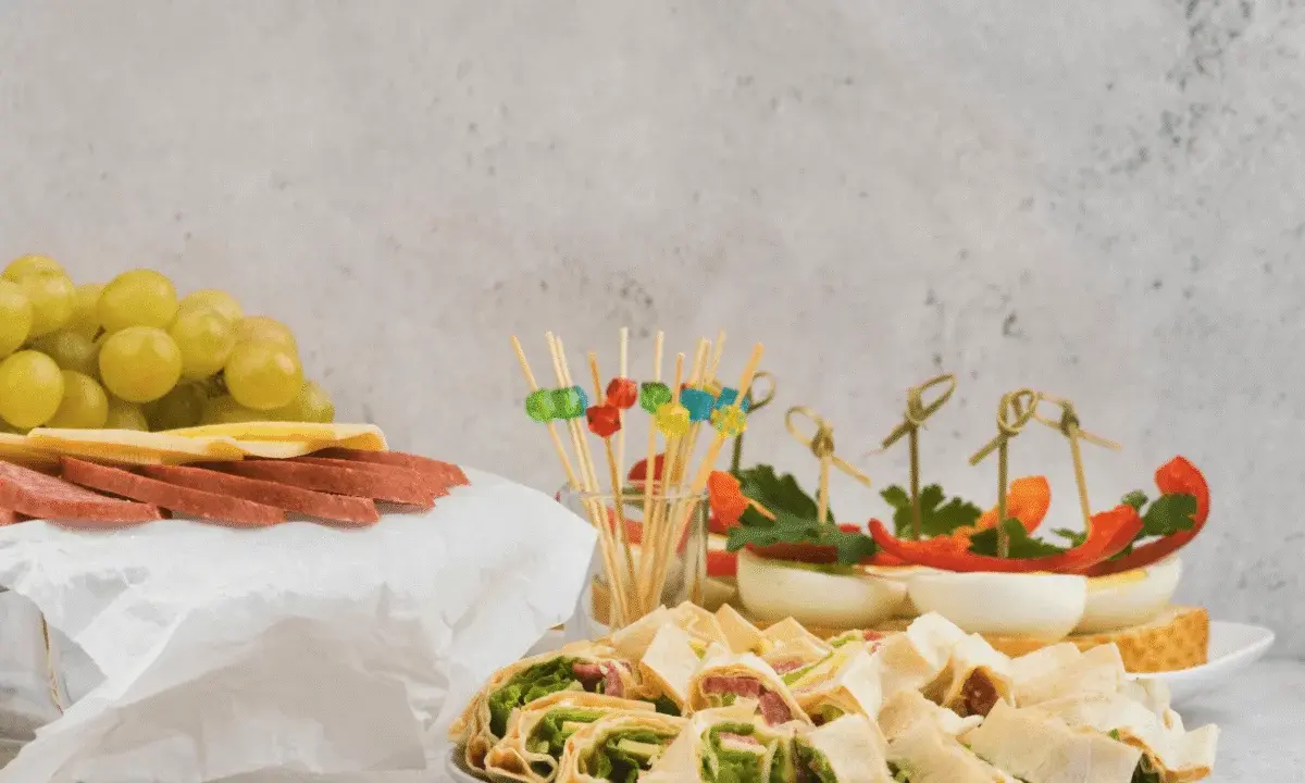 Kolorowe, zdrowe przekąski na imprezę: koreczki z warzywami, jajka faszerowane, roladki z tortilli, winogrona, ser i salami.