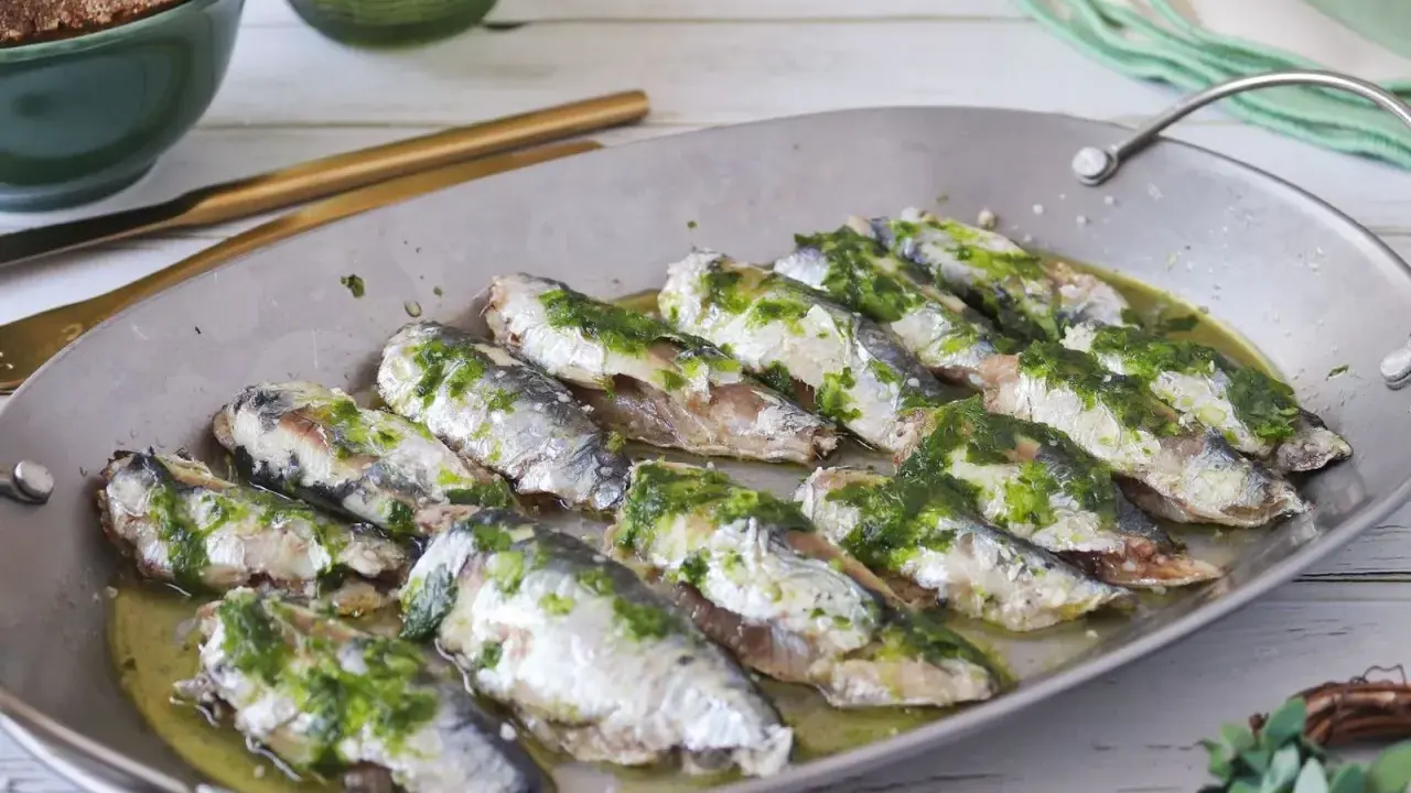 Deliciosas sardinas al horno, cubiertas con una sabrosa salsa verde, listas para disfrutar.