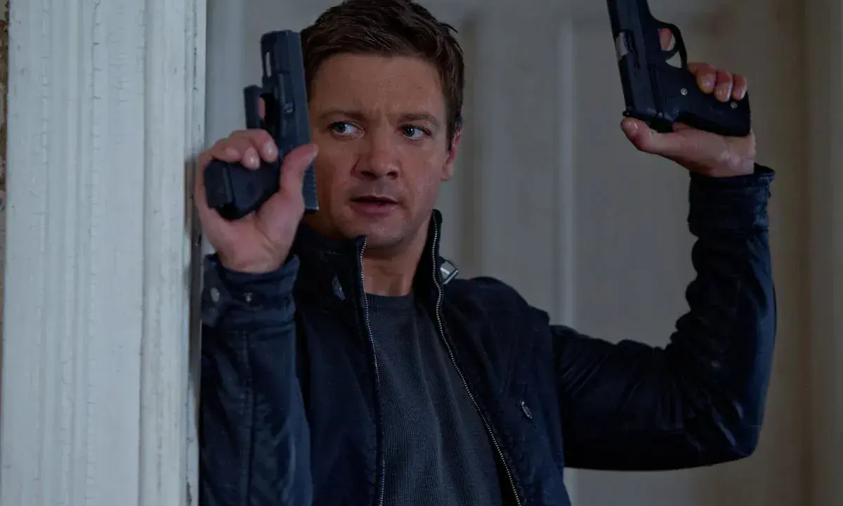 Jeremy Renner som Aaron Cross i rollistan i Jason Bourne-filmerna, redo för action med två pistoler.