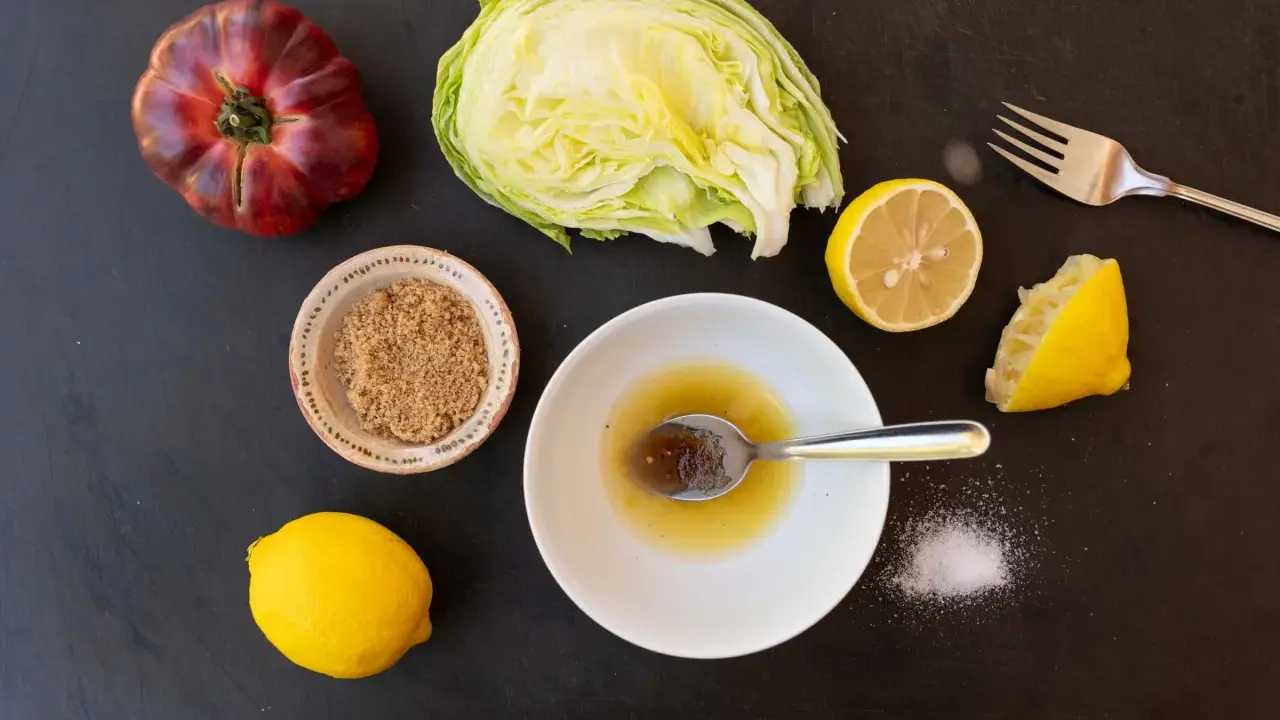 Zutaten für ein einfaches salatdressing mit zitrone und zucker: Eisbergsalat, Tomate, Zitronen, brauner Zucker und Salz.