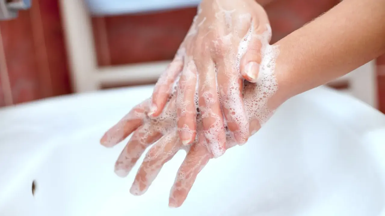 Mani insaponate che dimostrano come è fatto il sapone, creando una schiuma soffice per pulire.