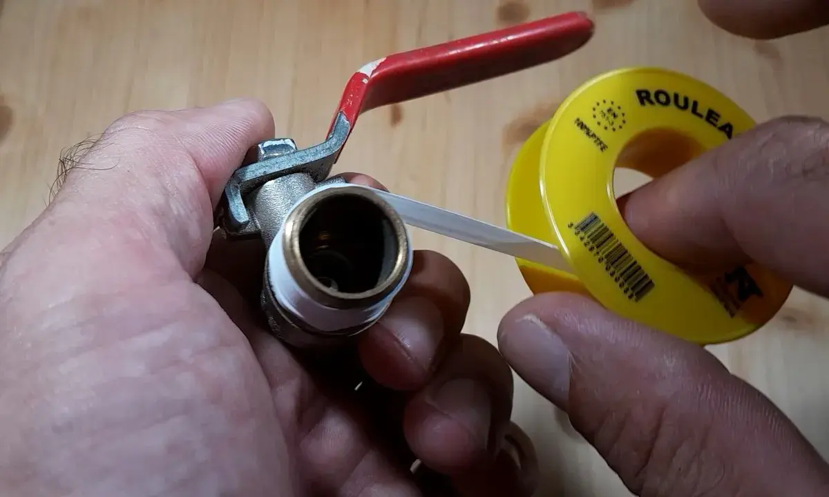 Main tenant une vanne, il applique du ruban de téflon pour assurer une étanchéité parfaite.