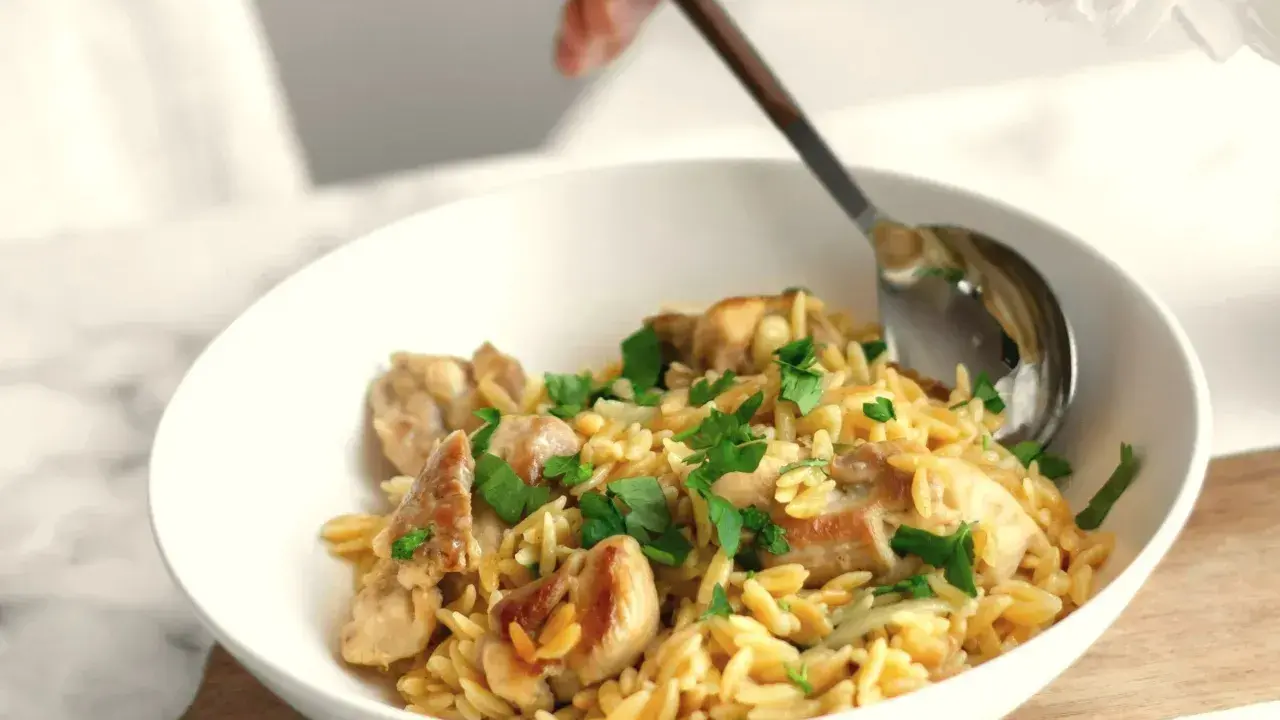 Szybki obiad z makaronem orzo i kurczakiem, posypany natką pietruszki. Idealny na szybki posiłek.