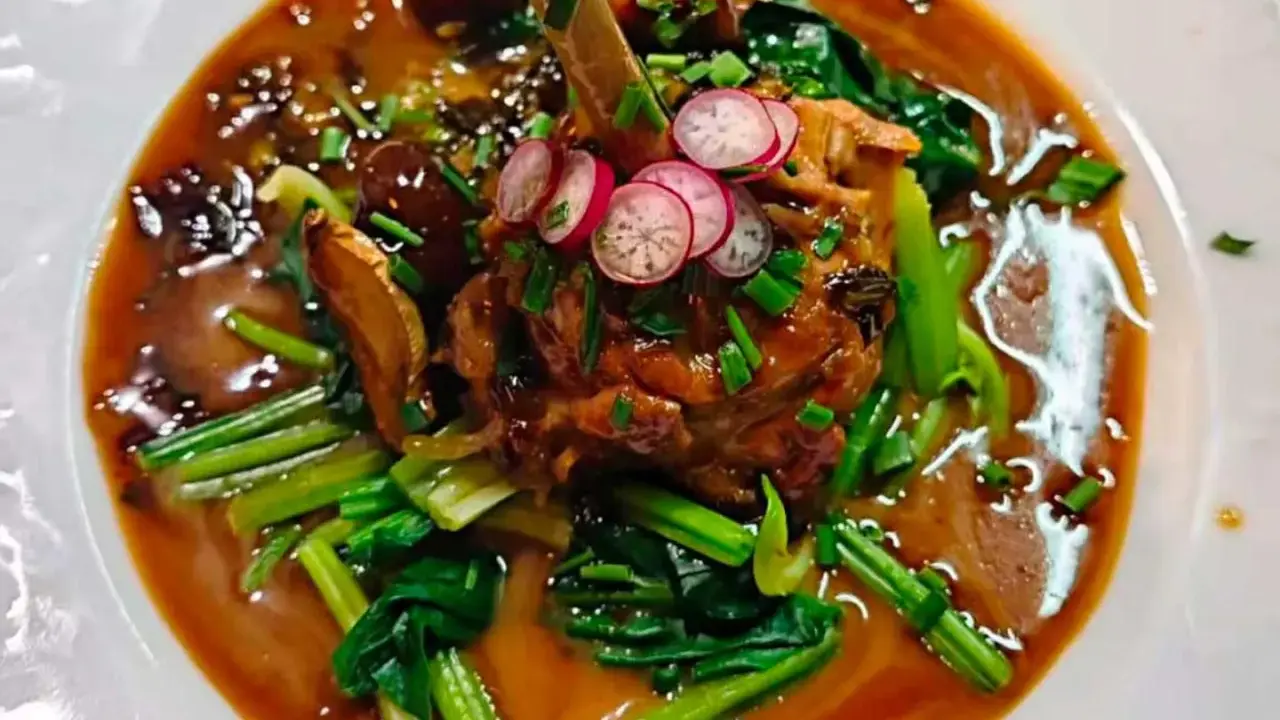 Un plat savoureux, un os de viande braisé dans une sauce riche, garni de radis et de légumes verts. Un aperçu des spécialités parisiennes.