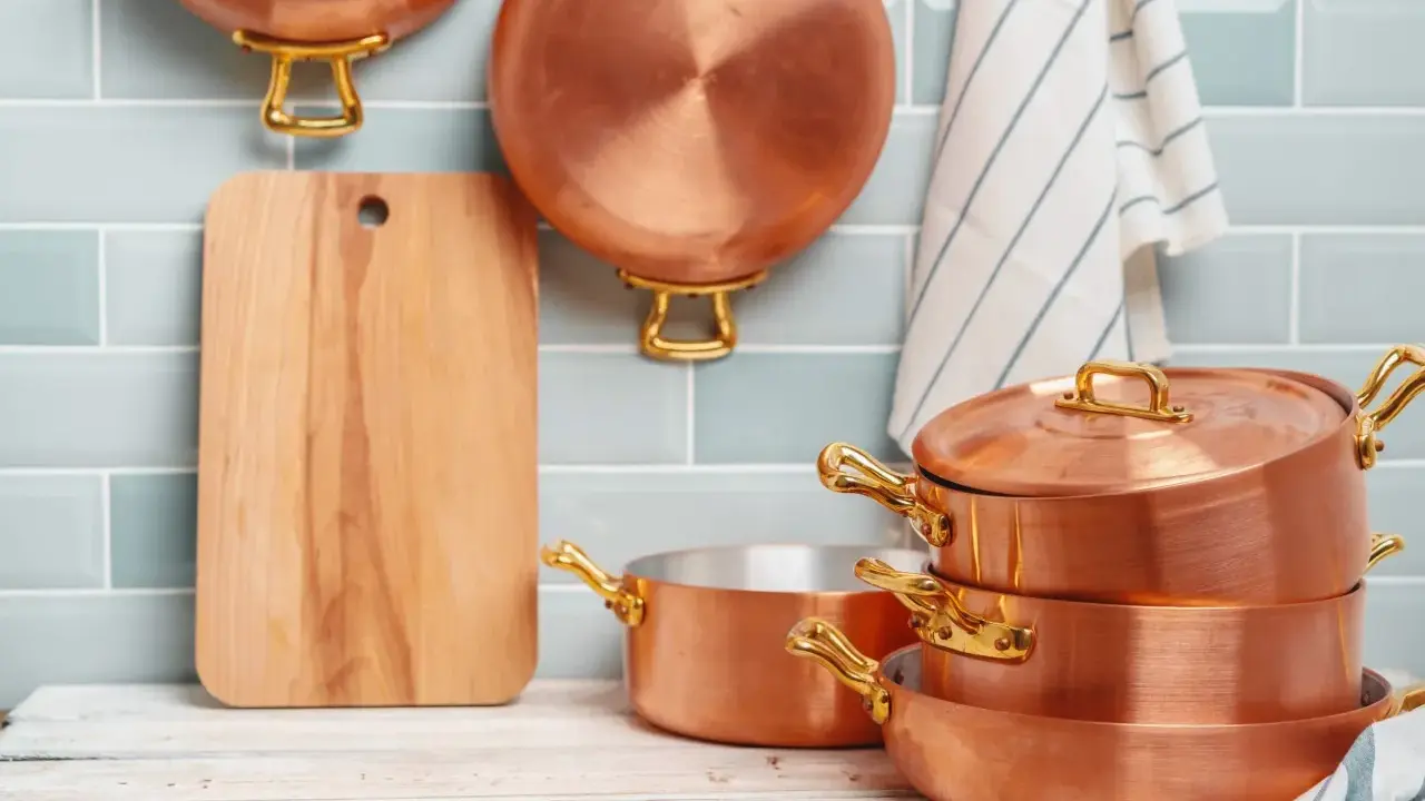 Utensilios de cobre apilados y colgados, listos para aprender como limpiar el cobre y mantenerlos brillantes.