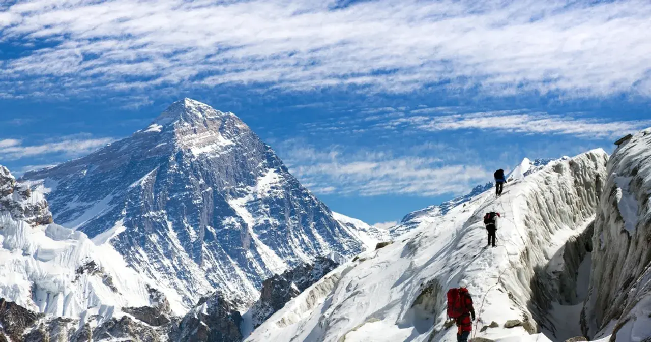 Alpinisci wspinają się na ośnieżony grzbiet, zbliżając się do jednego z najwyższych szczytów kontynentów.
