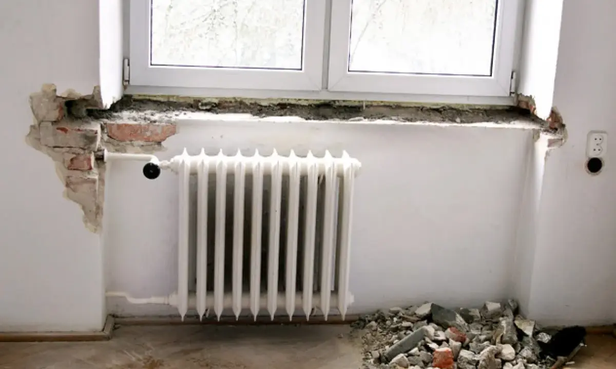 Rozpoczęła się wymiana parapetu wewnętrznego. Widać gruz pod oknem i odsłoniętą cegłę.
