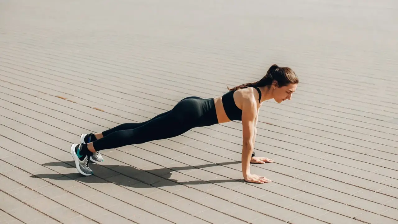 Femme en tenue de sport faisant une planche, un excellent exercice pour perdre du ventre.