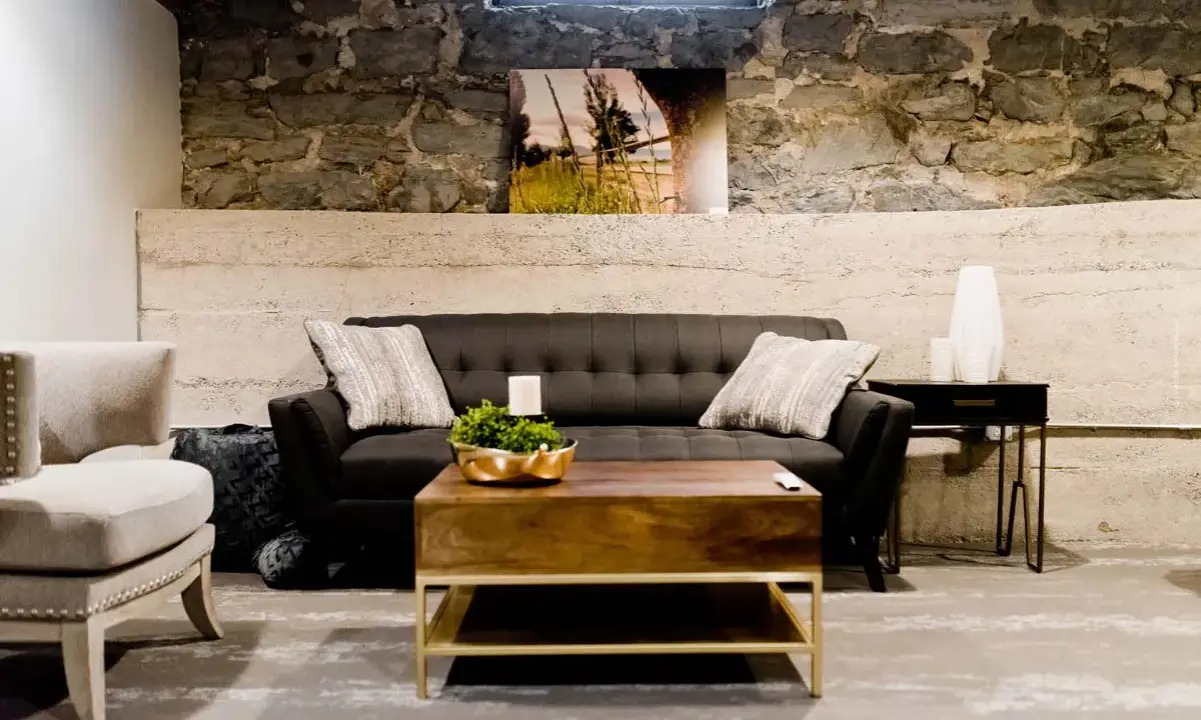 Gemütliches Wohnzimmer im industrial style mit dunklem Sofa, Holztisch und Steinwand.