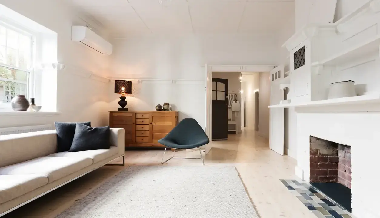 Salon lumineux avec canapé, fauteuil, buffet en bois et cheminée. Idéal pour savoir comment trouver un appartement rapidement.