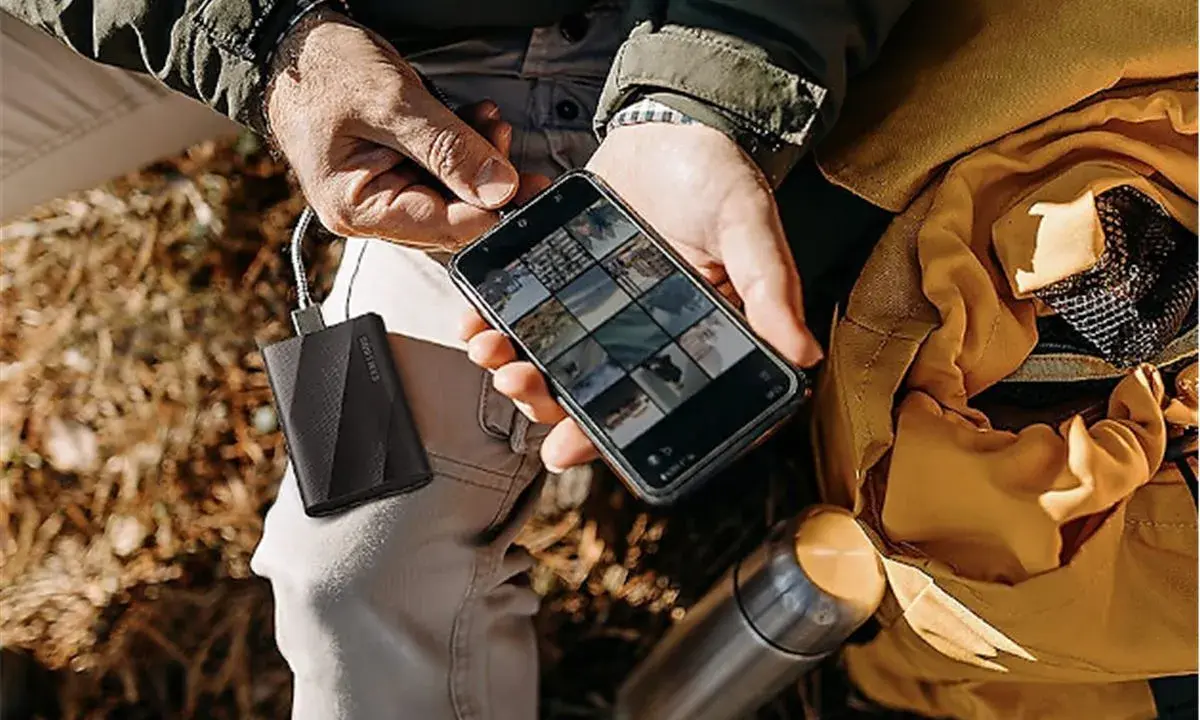 Un homme charge son téléphone avec une batterie externe, une aide précieuse pour comment organiser son téléphone et ses photos en voyage.
