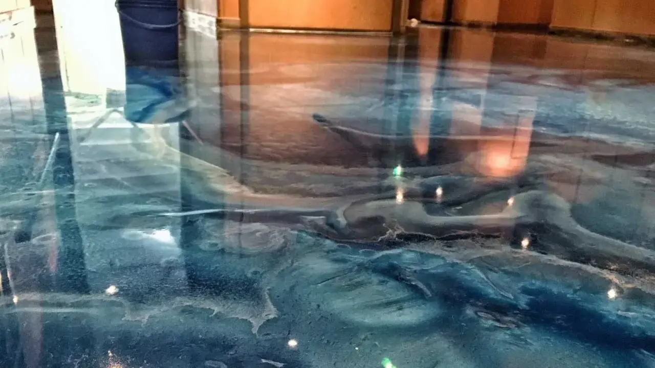 Glänzender Epoxidharzboden in Blau- und Brauntönen, der an eine Wasserlandschaft erinnert. Die Nachteile von Epoxidharz, wie die Empfindlichkeit gegenüber UV-Licht, sind hier nicht sichtbar.