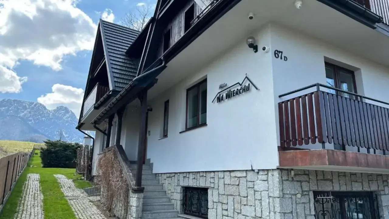 Willa Na Wierchu w Zakopanem, z kamienną podmurówką i drewnianymi elementami, wita gości pod malowniczymi Tatrami.