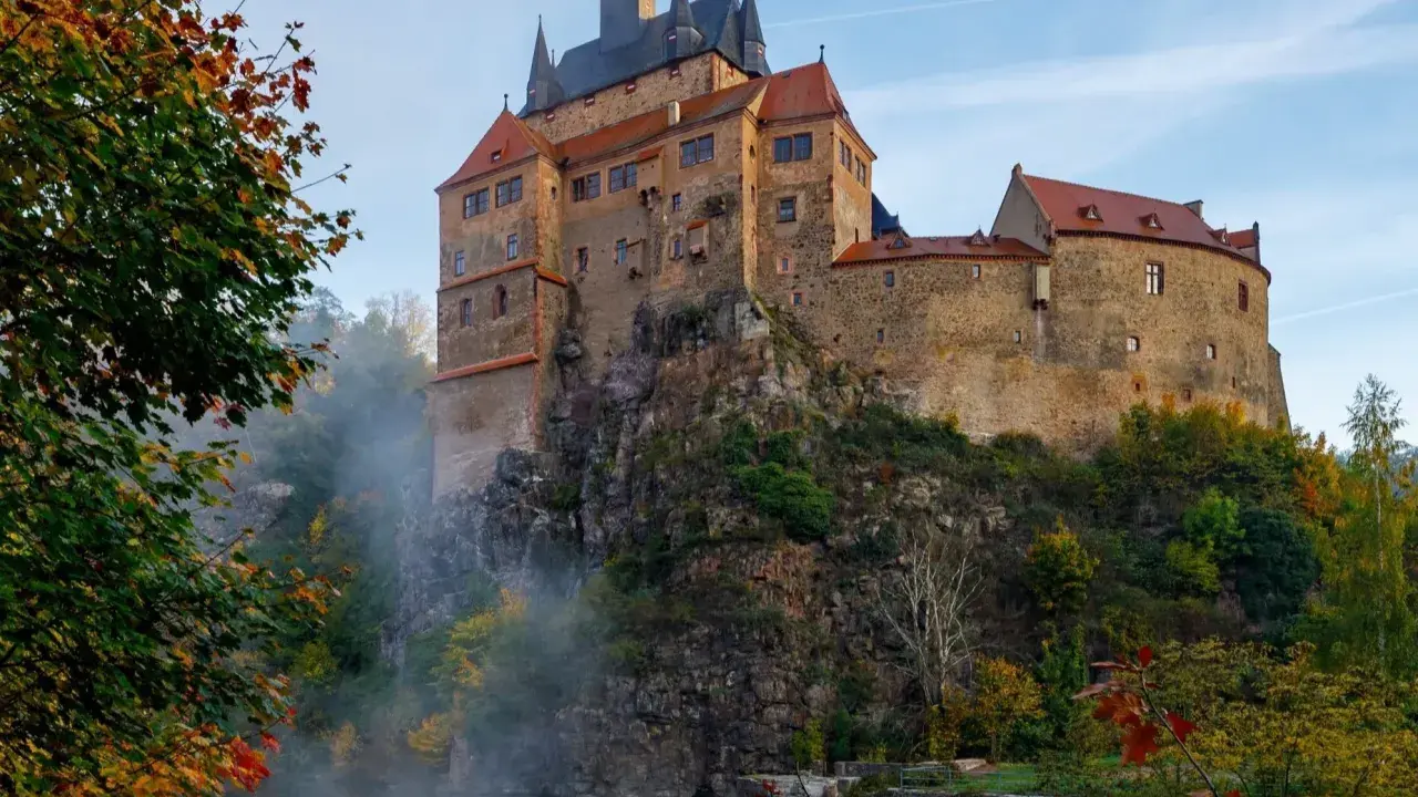 Zamek na skale nad wodospadem, jesienne liście i mgła tworzą malowniczy krajobraz. Wspaniałe wschodnie Niemcy atrakcje.