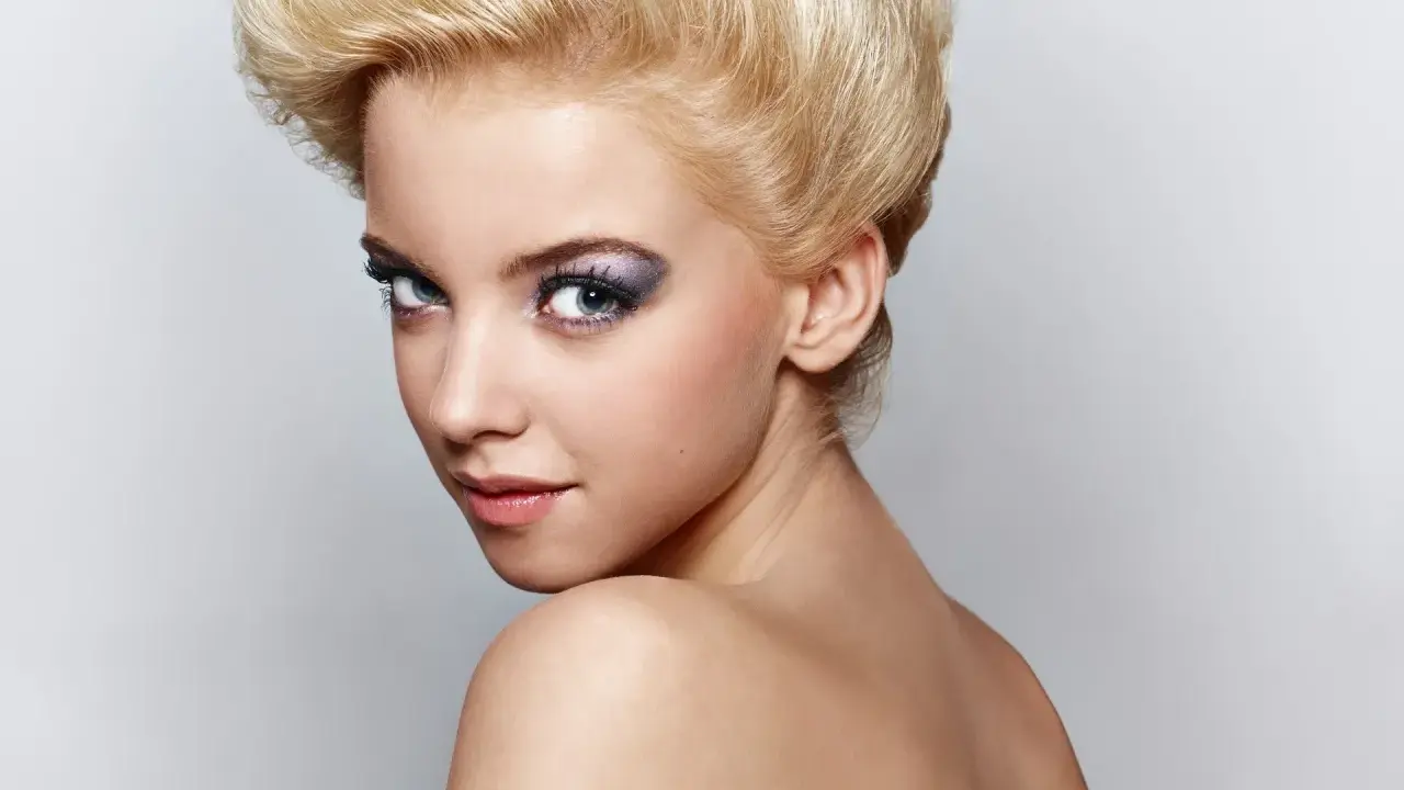 Mujer joven con peinado voluminoso y maquillaje llamativo, sus ojos de bambi cautivan la mirada.