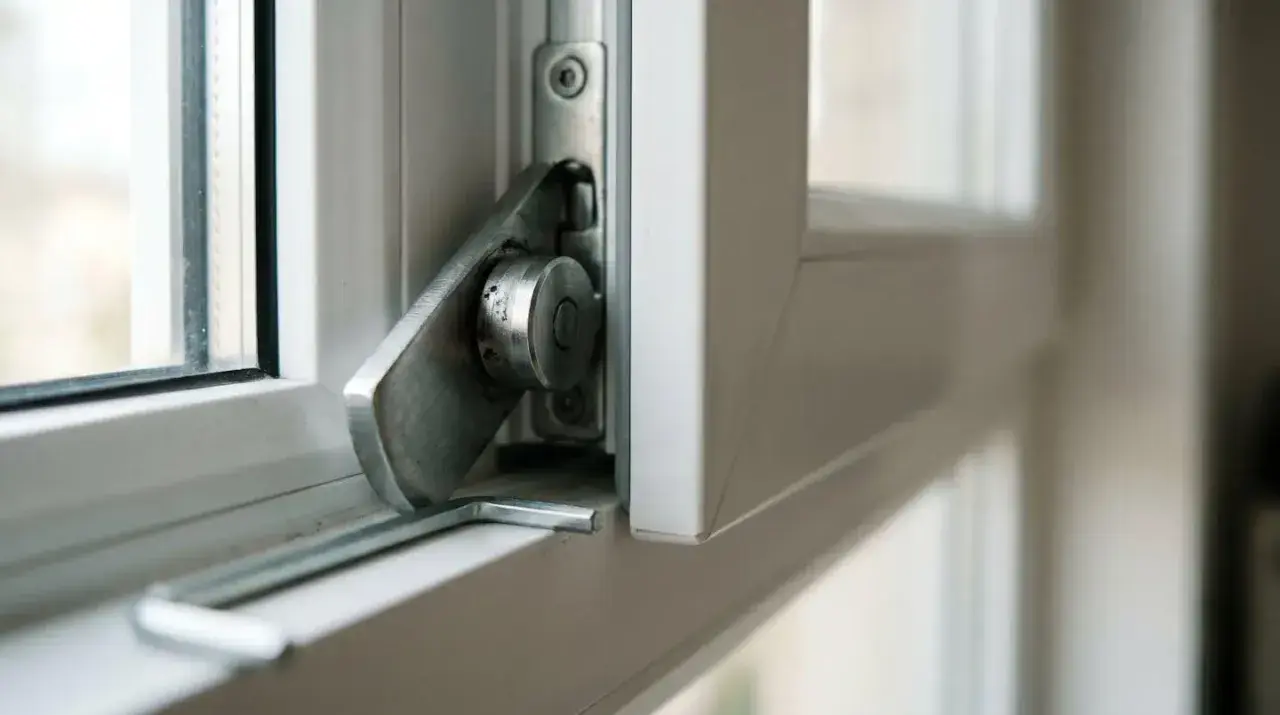 Detalle del mecanismo cierre ventana abatible, con palanca metálica y pivote.