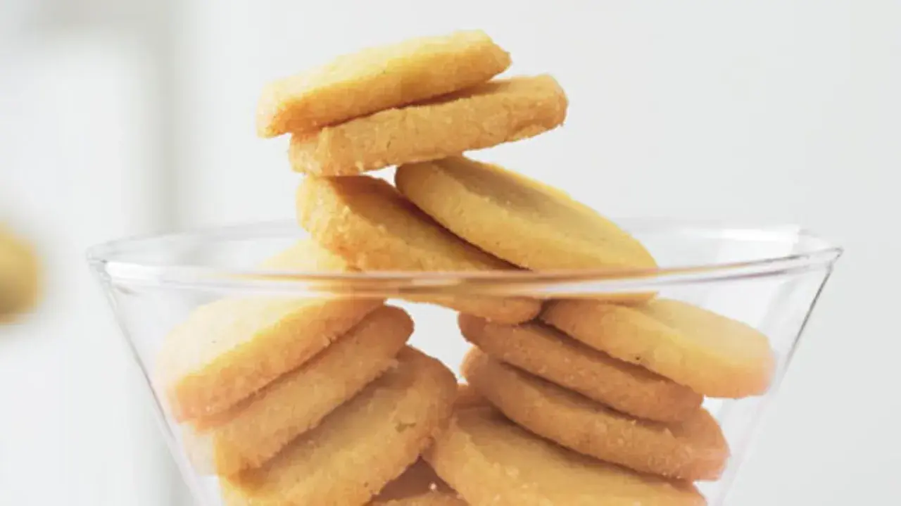Stapel von goldbraunen Heidesand-Keksen in einer Glasbowle. Dieses Bild weckt Lust auf das beste Heidesand Rezept!