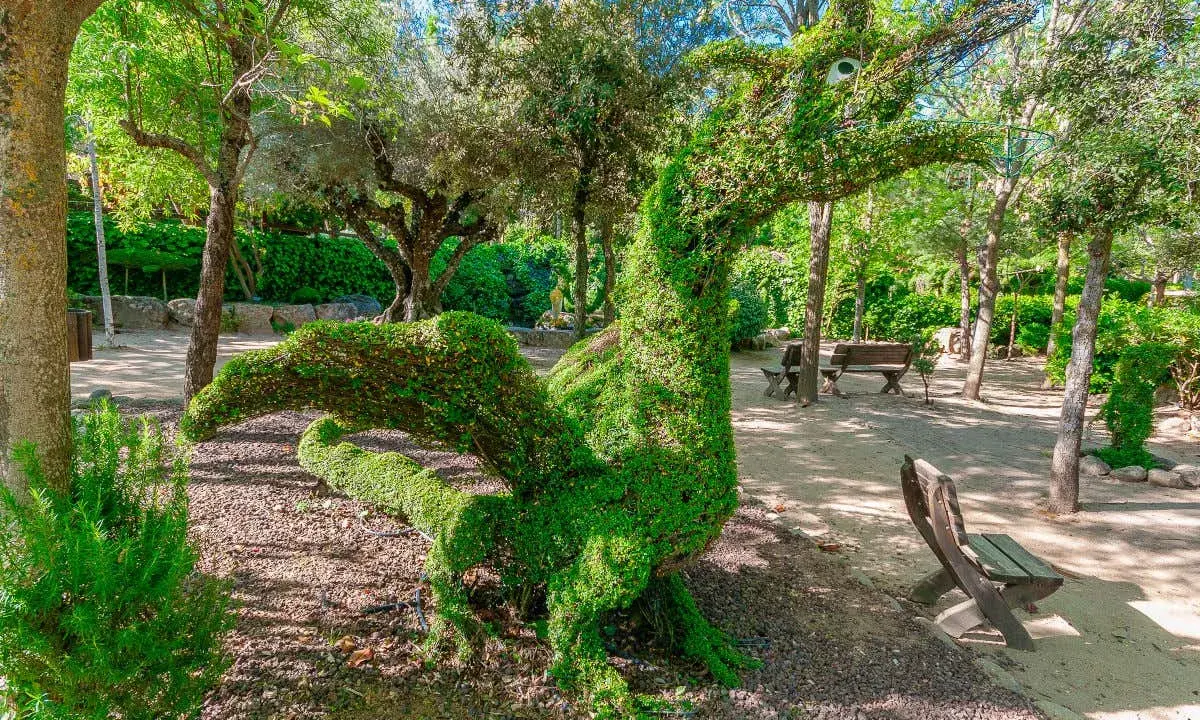 Un dragón de topiaria verde en un parque. Un lugar genial donde ver animales en Madrid, aunque este sea de plantas.