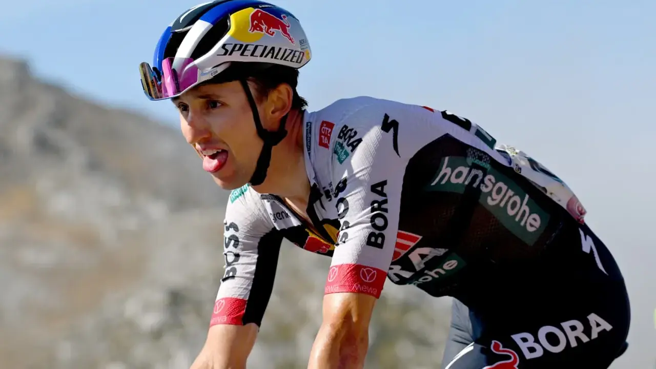 Radfahrer Jai Hindley kämpft sich mit herausgestreckter Zunge einen Berg hinauf, sein Helm trägt das Red Bull Logo.