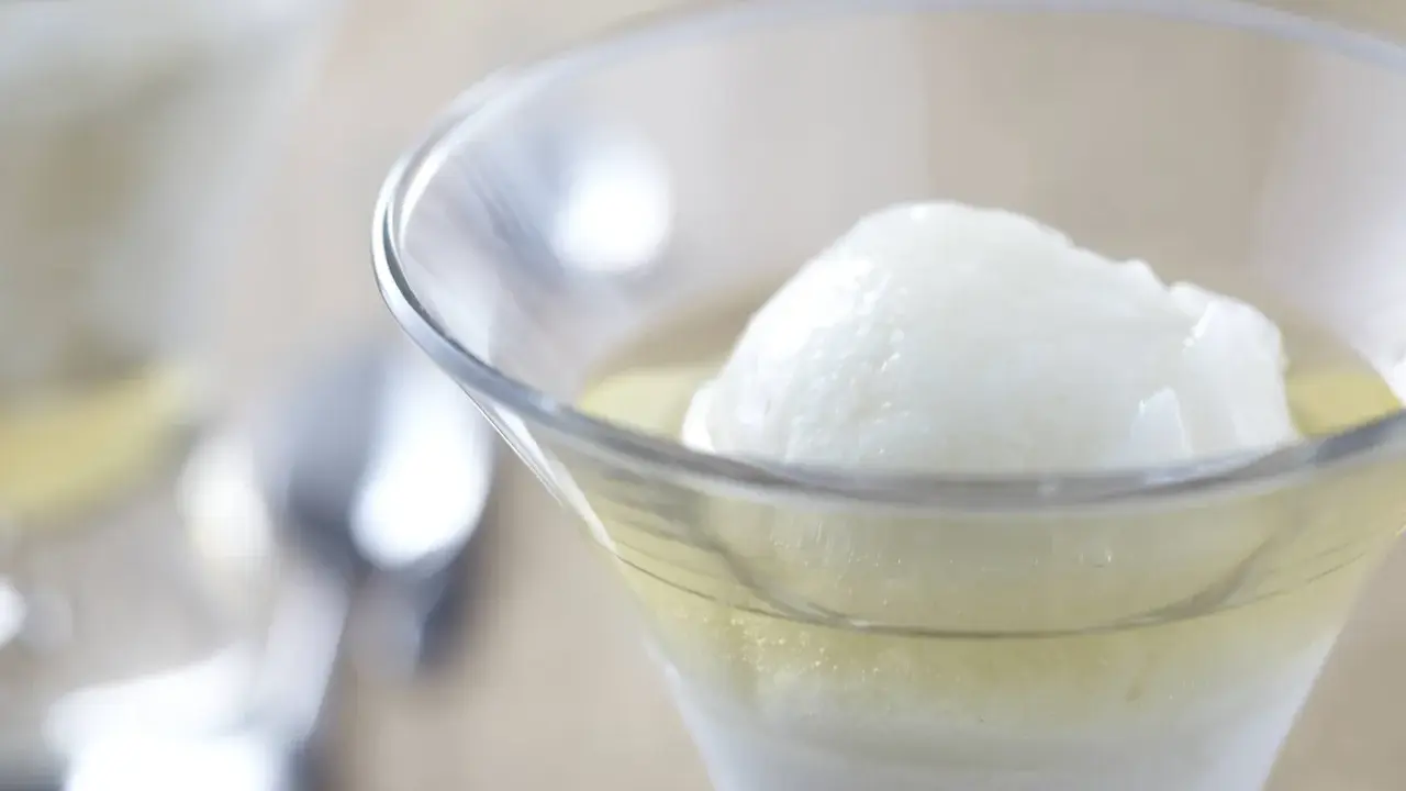 Une boule de sorbet citron dans un verre rempli de Calvados. Une recette de trou normand pour un dessert rafraîchissant.