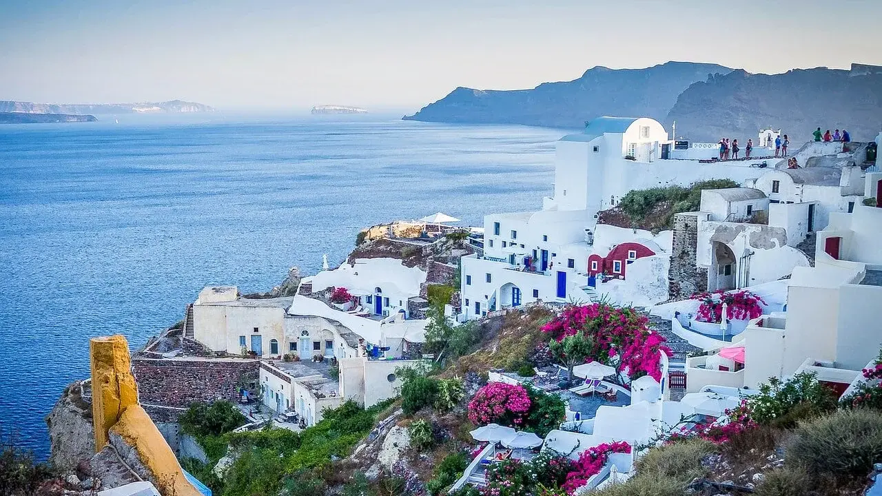 Białe domy na zboczu klifu z widokiem na morze, Santorini, Grecja.