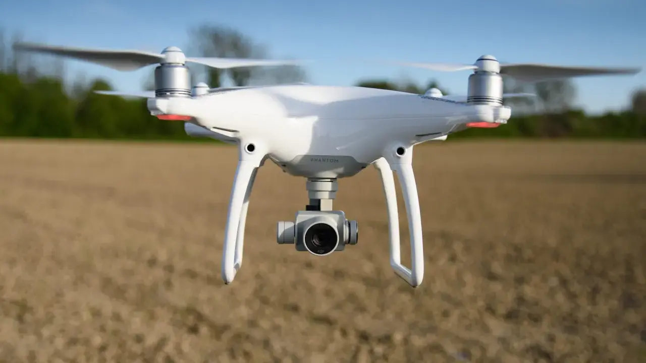 Biały dron DJI Phantom 4 Pro w locie nad polem.