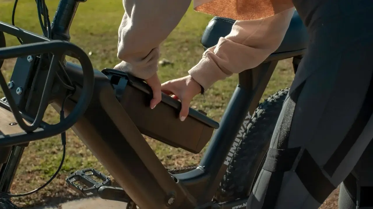 Osoba wyjmuje baterię z roweru elektrycznego, przygotowując się do ładowania.