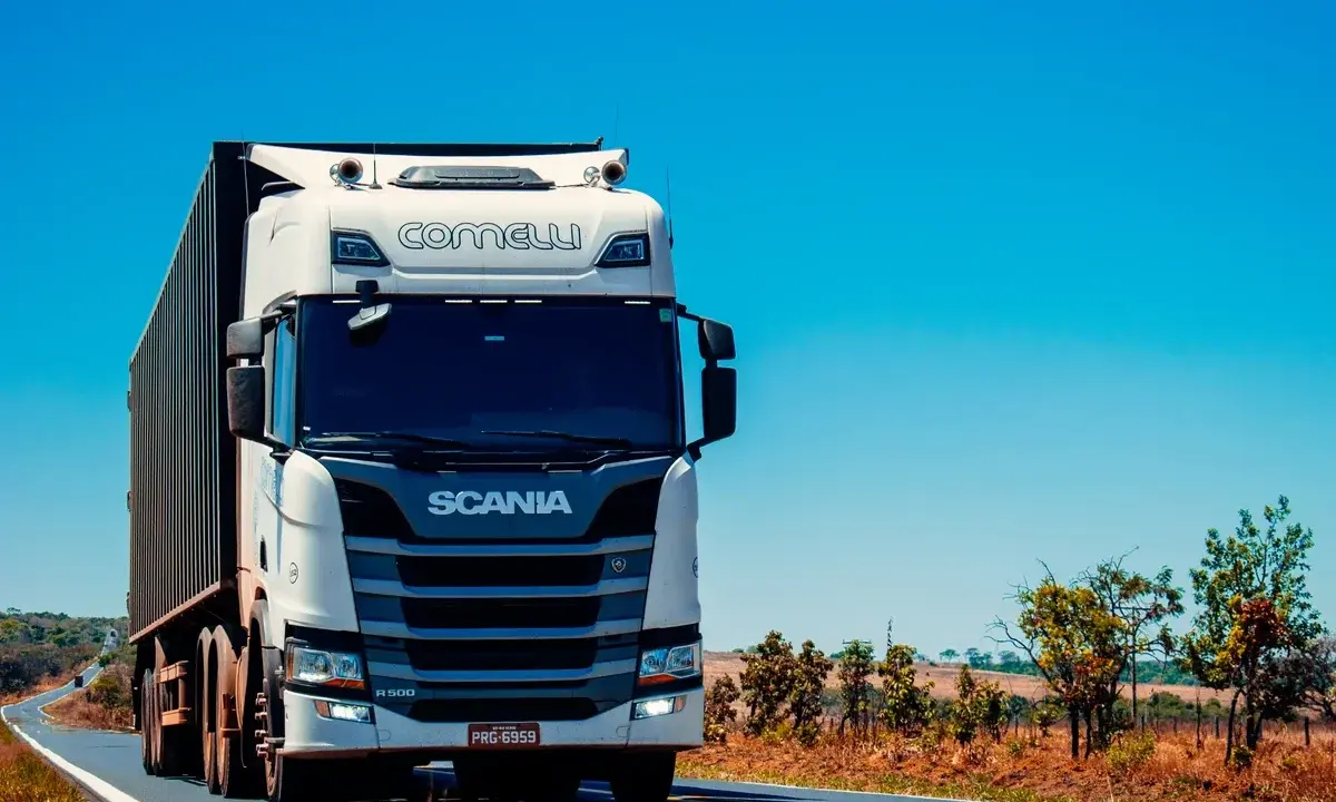 Camión Scania blanco en carretera soleada. Pensando en el coste del carnet de camión para conducir este gigante.