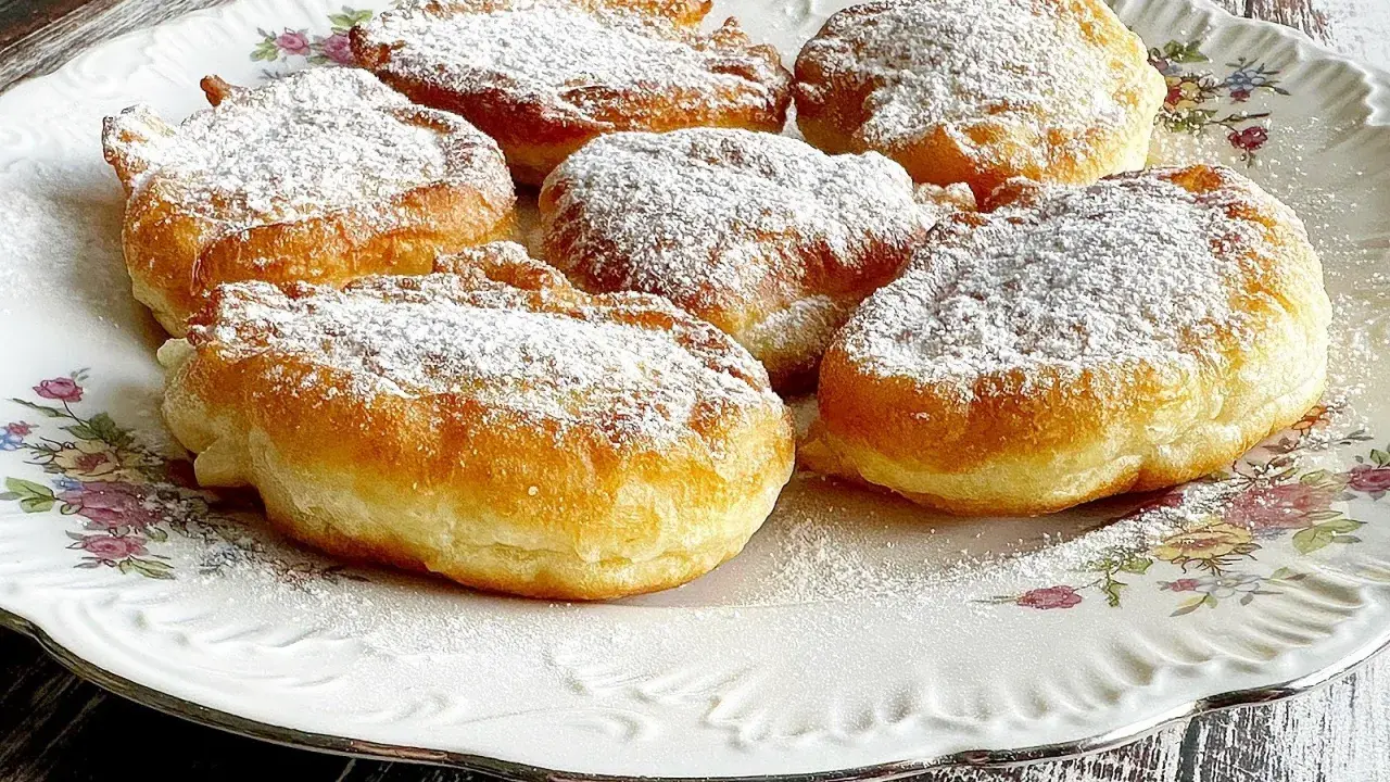 Puszyste racuchy z jabłkami na jogurcie, posypane cukrem pudrem, kuszą swoim wyglądem.