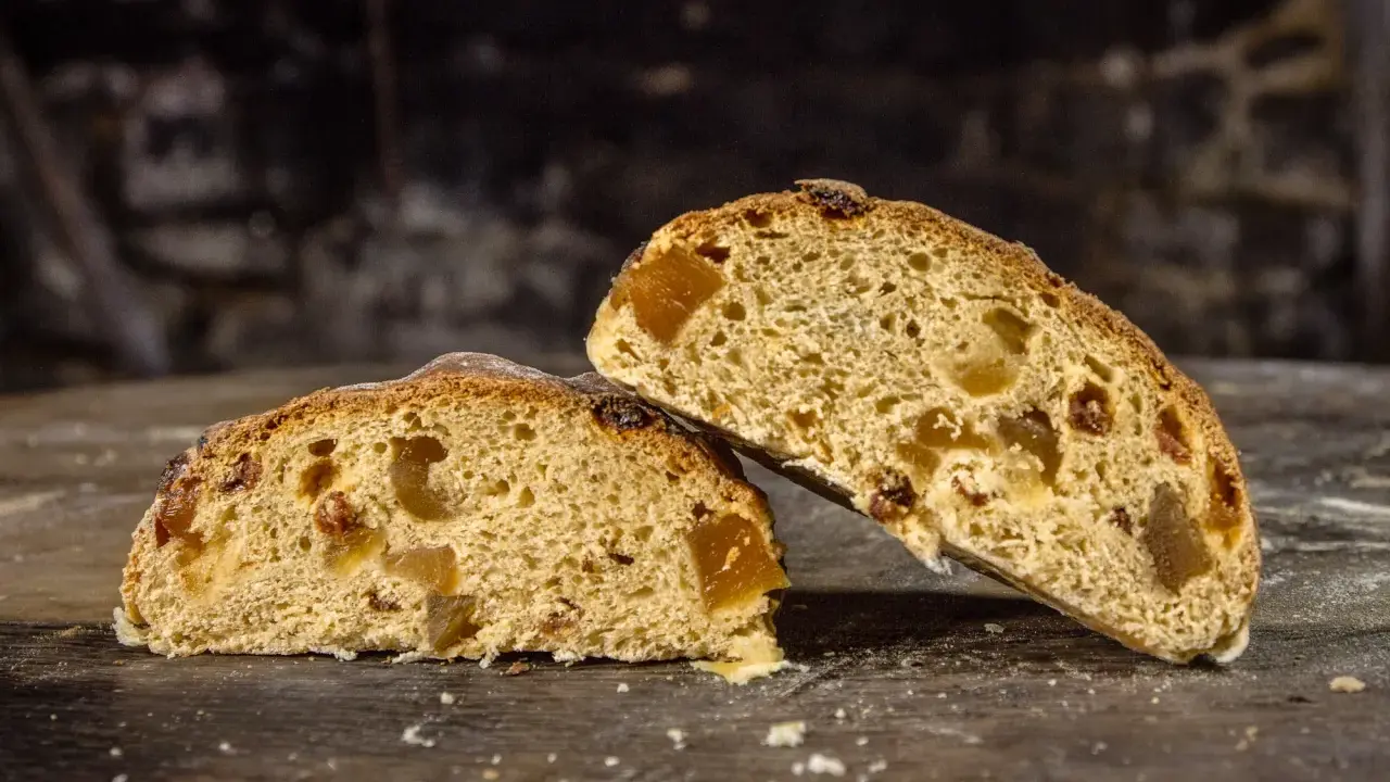 Deux tranches de pain au levain de gingembre, garnies de fruits confits, sur une table en bois rustique.