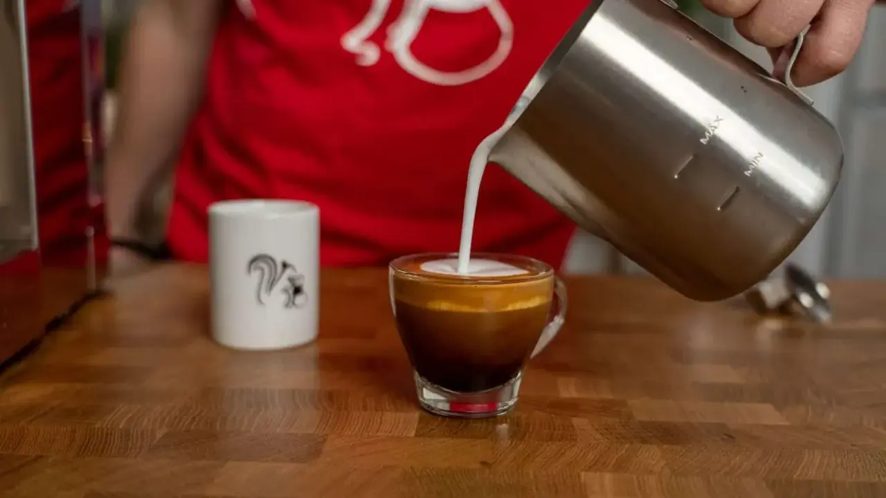 Milchschaum fließt in einen Espresso, um einen perfekten Espresso Macchiato zu kreieren.