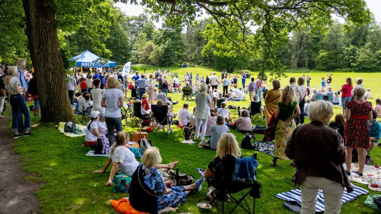 Midsommar i Slottsskogen samlar folk för picknick och gemenskap under trädens skugga.