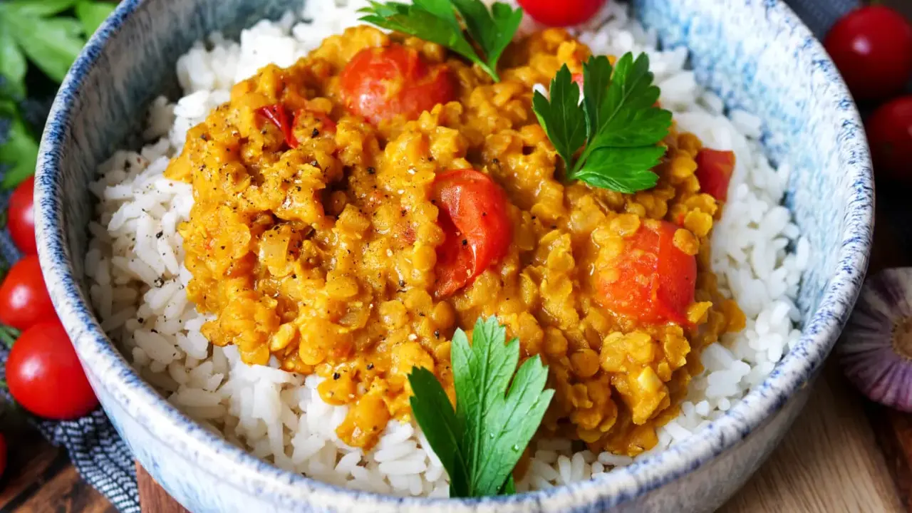 Herzhaftes rote Linsen Curry mit Reis, garniert mit frischer Petersilie und Kirschtomaten. Ein Genuss für die Sinne!